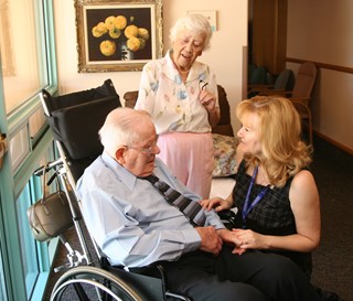 Older male in wheel chair with two females standing beside him