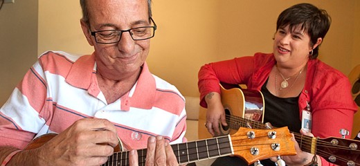 Music volunteer playing guitar with patient