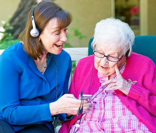 Maribeth Gallagher listens to music and sings with a dementia patient