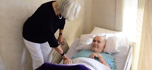 Healthcare worker helps male patient adjust in bed