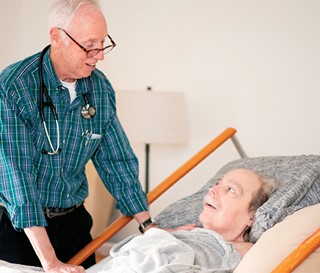 John Williams, MD Medical Director, talk with patient lying in bed