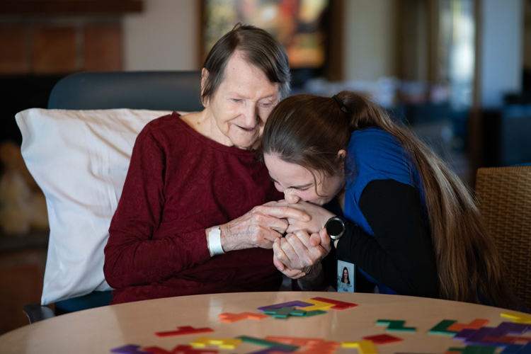 Caregiver kissing hand of dementia patient