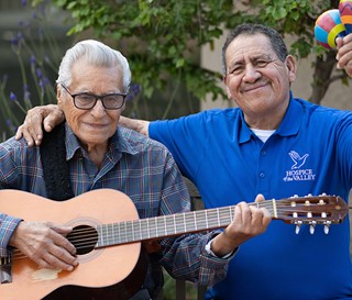 Hispanic dementia patient Feliciano Ordonez playing guitar with nurse