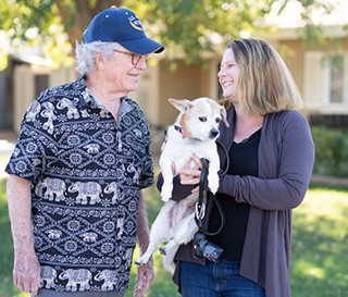 Navy veteran Larry Lambert enjoys the daily walks and friendship provided by Legacy Corps volunteer Meredith Bartlett, holding his dog, Molly.