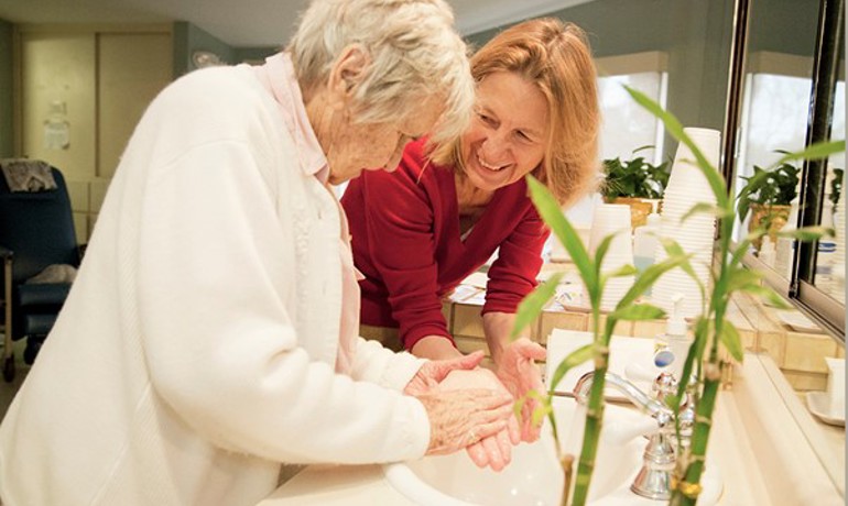 HOV employee and patient smile together while washing their hands in a sink
