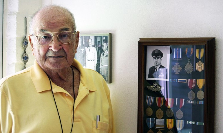Man standing next to framed medals