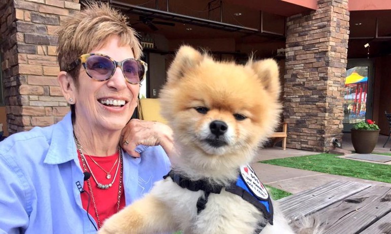 A volunteer smiles with her therapy dog