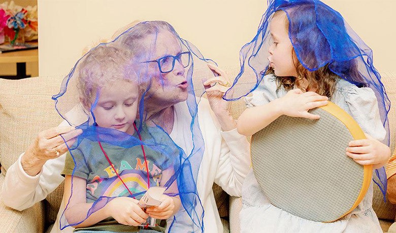 Adult Day Club participant playing with two young children