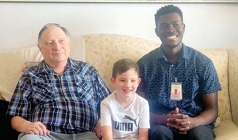 A HOV volunteer smiles with an HOV patient and the patient's grandson.