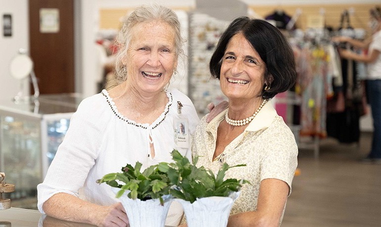 2 White Dove volunteers at the front desk of the store
