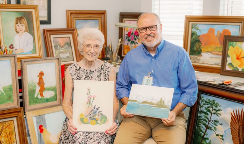 Artist Avinell MacDonald and chaplain Ken Collins pose with their art
