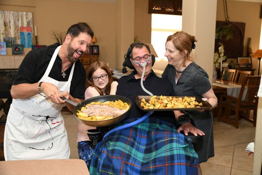 Volunteer Jeff Riddle poses with Mark Adinolfi, his wife Jeane and daughter Sophia and the food they've prepared