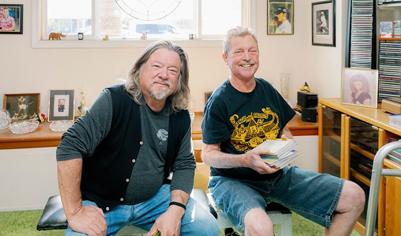 David Roberts smiling with his music collection and concert promoter Danny Zelisko