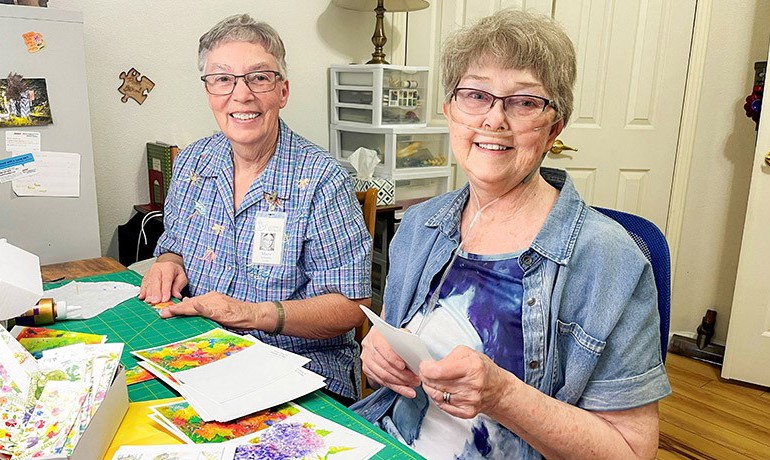 Patient and volunteer sitting in an art room making handmade cards