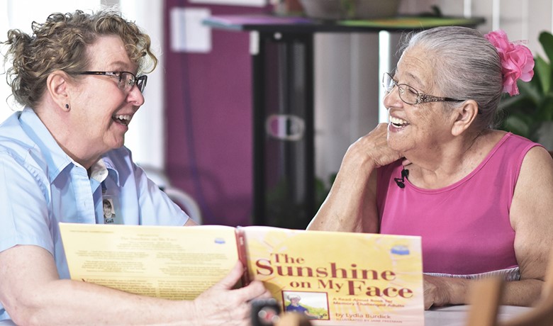 Gail Higgenbotham reads a book with patient Tomasa