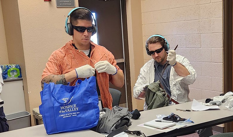 Two police officers complete tasks while wearing items meant to simulate dementia experience