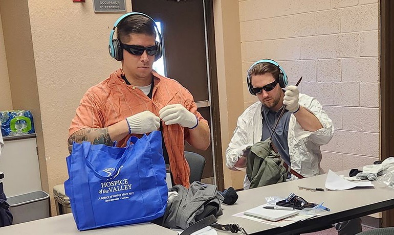Two police officers complete tasks while wearing items meant to simulate dementia experience