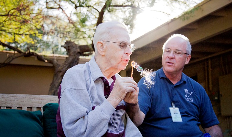 Patient blowing bubbles with caretaker