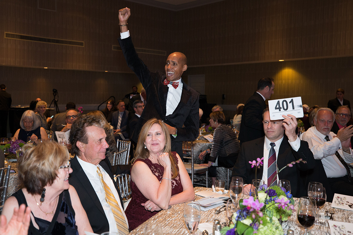 Auction assistant standing behind bidder at table 