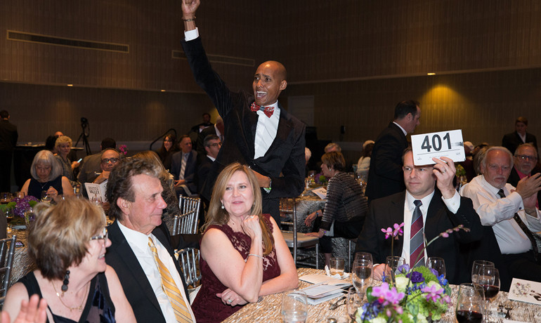 Auction assistant standing behind bidder at table 