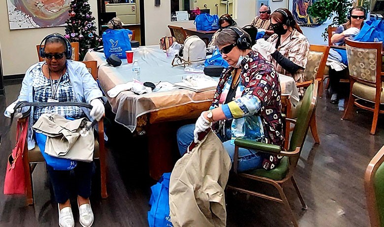 Dementia workshop participants wearing gloves, sunglasses and headphones
