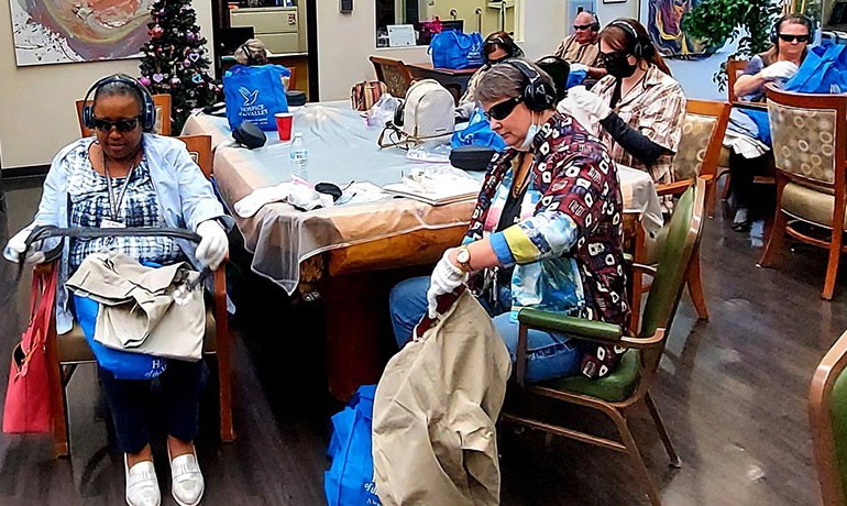 Dementia workshop participants wearing gloves, sunglasses and headphones