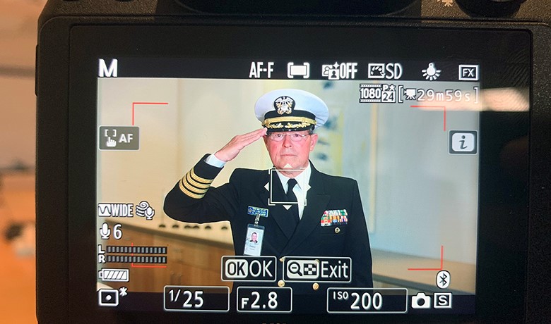 Camera screen showing camera settings and image of Denny Bash saluting