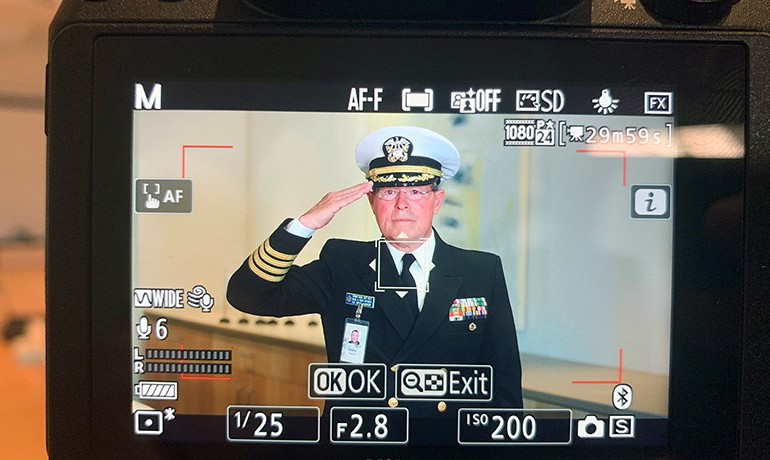 Camera screen showing camera settings and image of Denny Bash saluting
