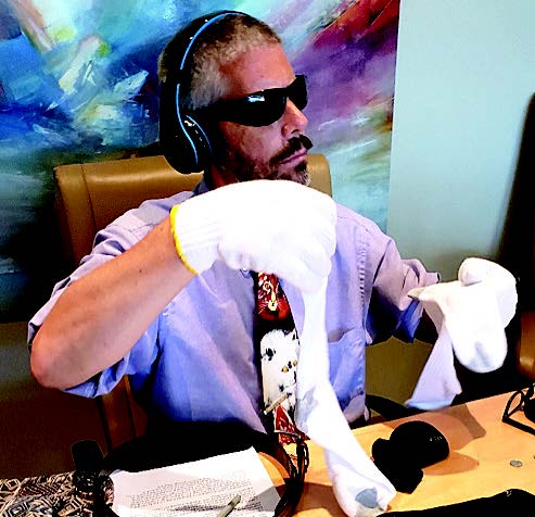 Man wearing dementia simulation gloves, goggles, and headphones