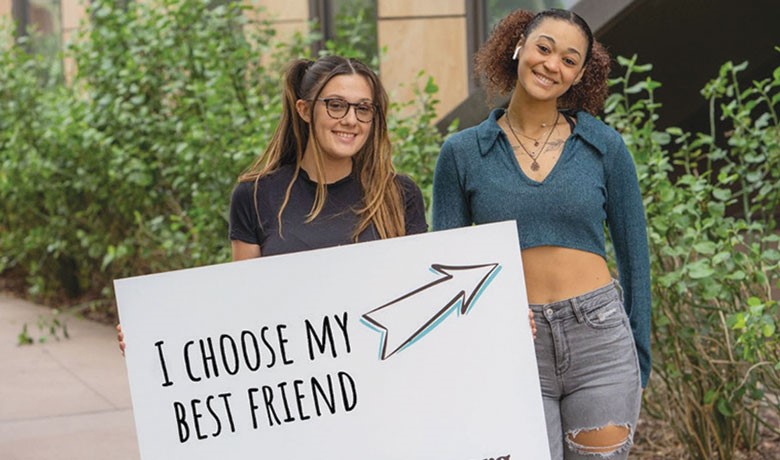 Two women posing together with sign saying, "I choose my best friend."